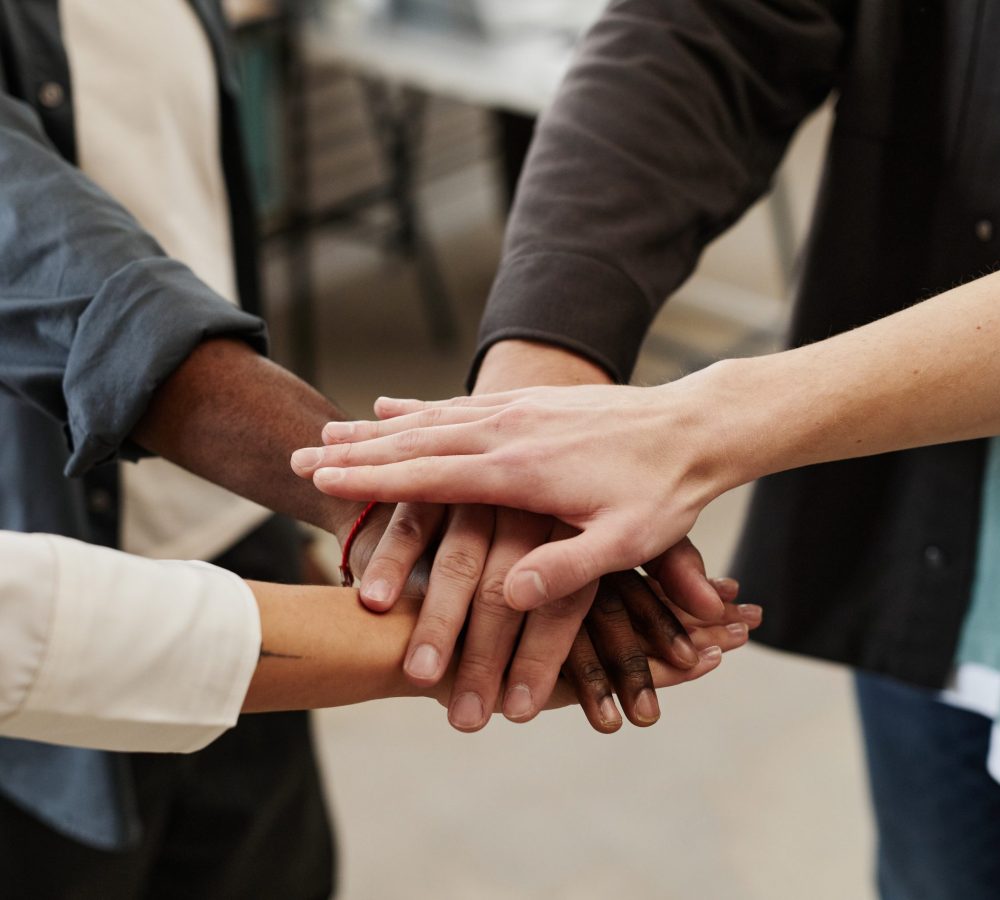 Close-up of business people holding hands during their teamwork at office